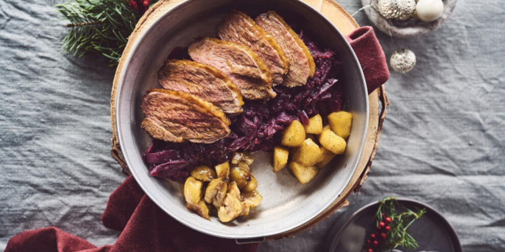 Sliced duck glazed with orange on braised red cabbage with apples and chestnuts